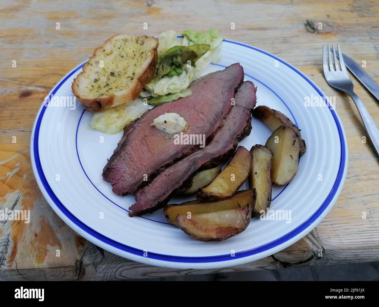 Roastbeef mit Kartoffeln und Knobauchbaguette Foto Stock