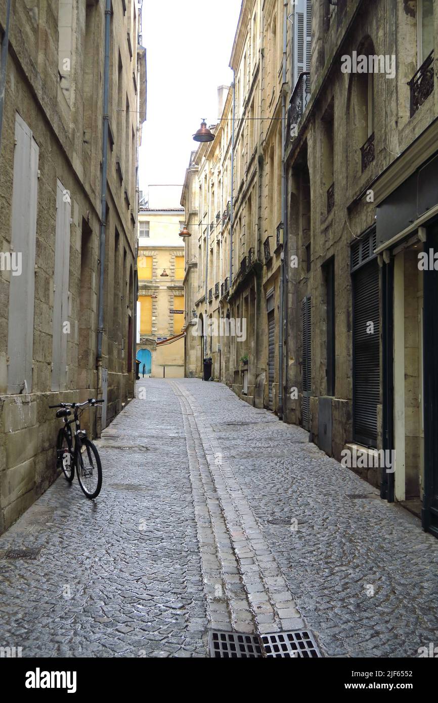 Una bicicletta si appoggia contro un muro su una strada acciottolata nella città francese di Bordeaux Foto Stock