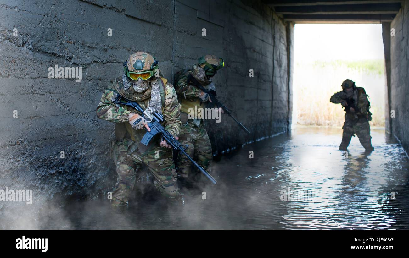 Foto di tre mercenari militari durante un'operazione speciale sullo sfondo di un tunnel di cemento di bunker sotterraneo e fumo. Collage - Foto Stock