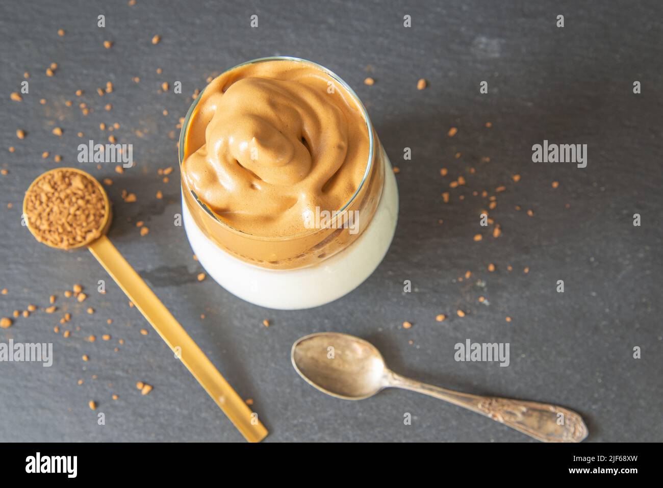 Caffè Dalgona. Bevanda ghiacciata a base di caffè in stile coreano su sfondo scuro. Caffè istantaneo con zucchero e acqua per una colazione gustosa. Molto alla moda co Foto Stock