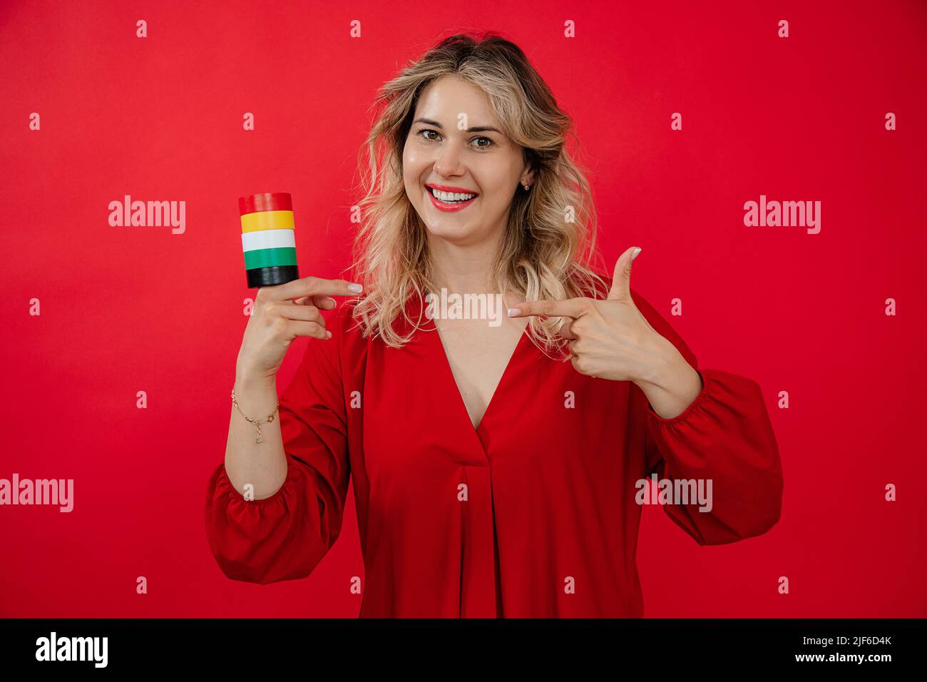 Bionda bella donna che tiene in mano rotolo set di condotto isolamento nastro su sfondo rosso Foto Stock
