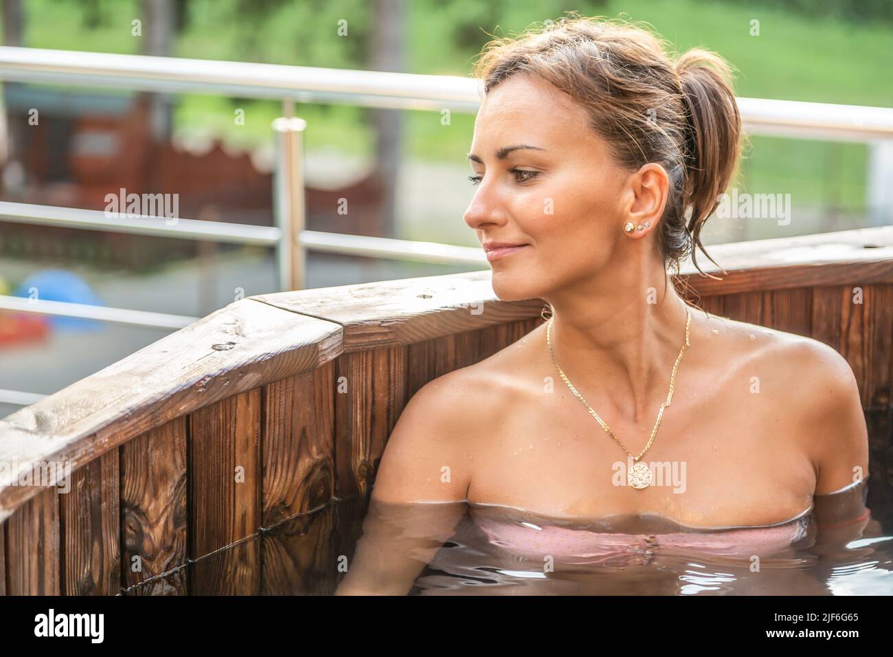 Giovane donna che si gode la vacanza estiva nella spa all'aperto in vasca di legno. Foto Stock