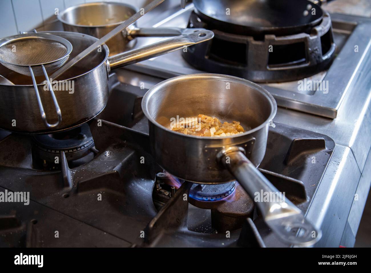 Primo piano di padella con riso e carne che viene cucinato in cima alla stufa in cucina commerciale Foto Stock