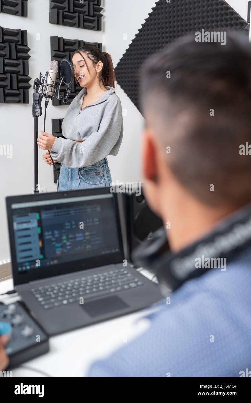 Giovane cantante femminile che registra voce nel microfono presso lo studio di musica Foto Stock