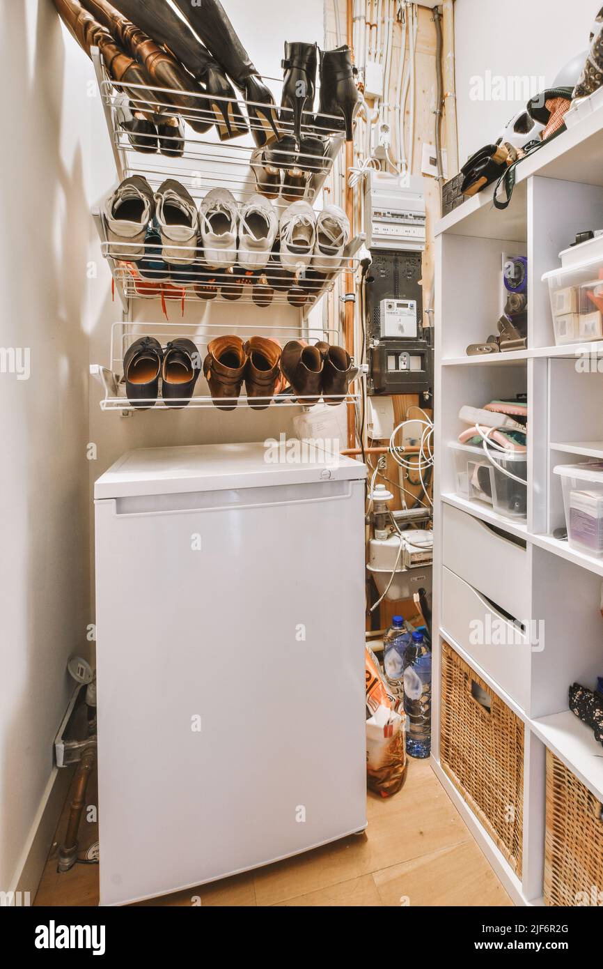 Moderno congelatore elettrico bianco sotto scaffale vicino a varie scarpe in deposito Foto Stock