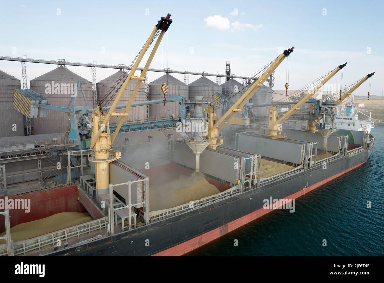 Carico di grano in stive di nave da carico via mare attraverso una linea automatica in porto marittimo da sili di deposito di grano. Bunkering di nave di carico asciutta con grano Foto Stock