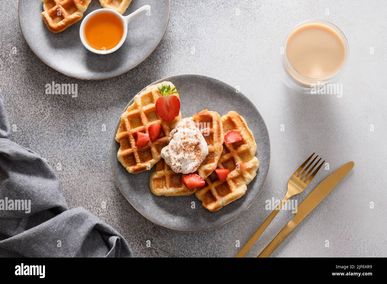 Colazione alla moda con crostini e caffè del mattino, fragole su sfondo grigio. Croissant come waffle. Vista dall'alto. Foto Stock