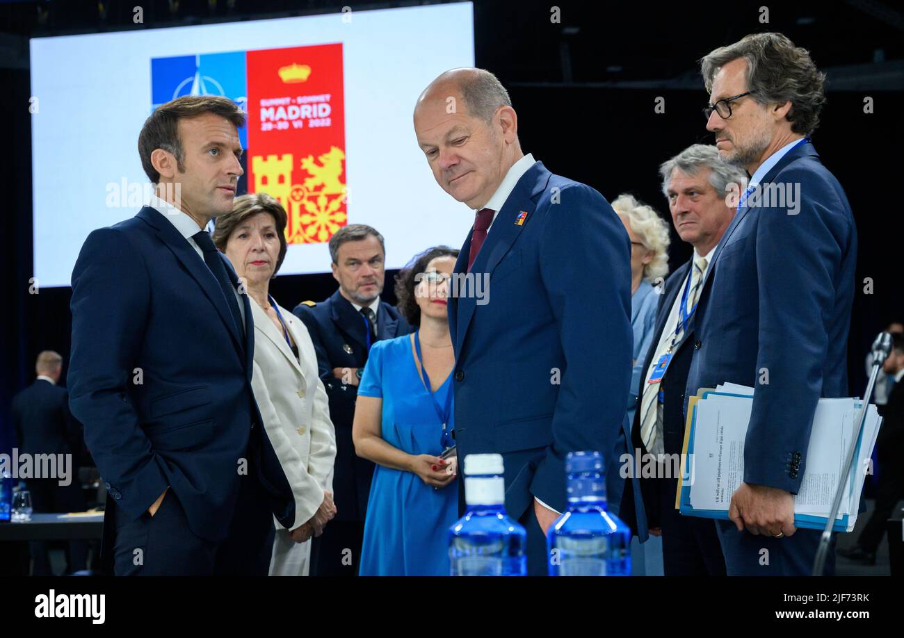 30 giugno 2022, Spagna, Madrid: Emmanuel Macron (l), presidente della Francia, ha parlato con il cancelliere tedesco OLAF Scholz (M, SPD) e Jens Plötner (r), consigliere per la politica estera e di sicurezza presso la Cancelleria federale, all'inizio dell'ultima sessione di lavoro al vertice NATO di Madrid. Dietro di loro vi sono Rüdiger König, rappresentante permanente della Germania presso la NATO, e Christine Lambrecht (SPD), ministro tedesco della Difesa, e Catherine colonna (2nd da sinistra), ministro degli Esteri della Francia. Al vertice di due giorni, i capi di Stato e di governo dei 30 stati dell'alleanza hanno preso decisioni sull'attuazione o Foto Stock