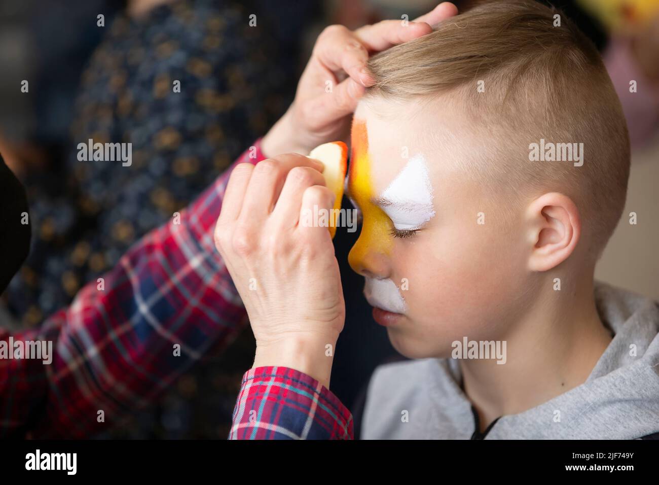 Make artist disegna la pittura facciale sul volto di un ragazzino. Foto Stock