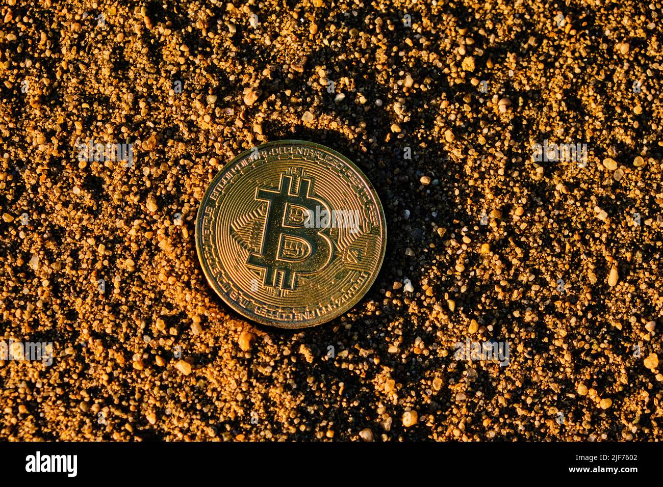 Moneta di Bitcoin nella sabbia al tramonto, crollo e caduta criptovaluta Foto Stock