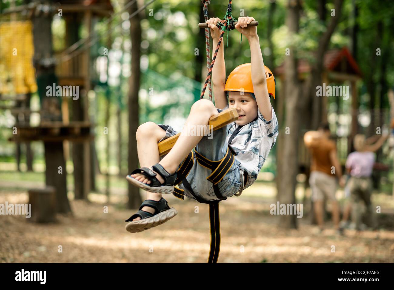 Un ragazzo è appeso sulla linea nel parco funi. Animazione sportiva per un bambino, riposo attivo. Foto Stock
