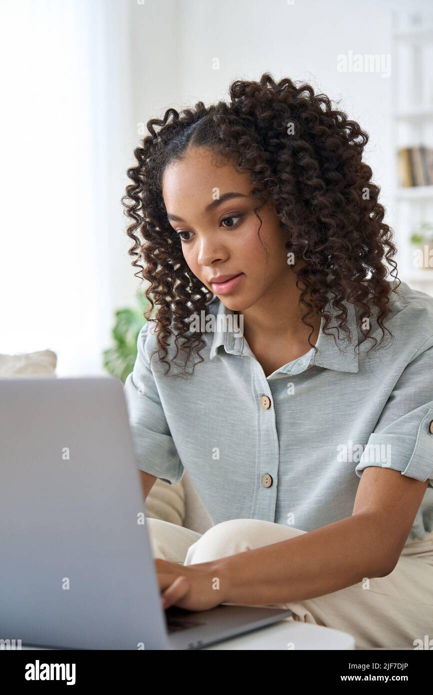 Giovane ragazza afroamericana che guarda i video online usando il portatile a casa. Foto Stock