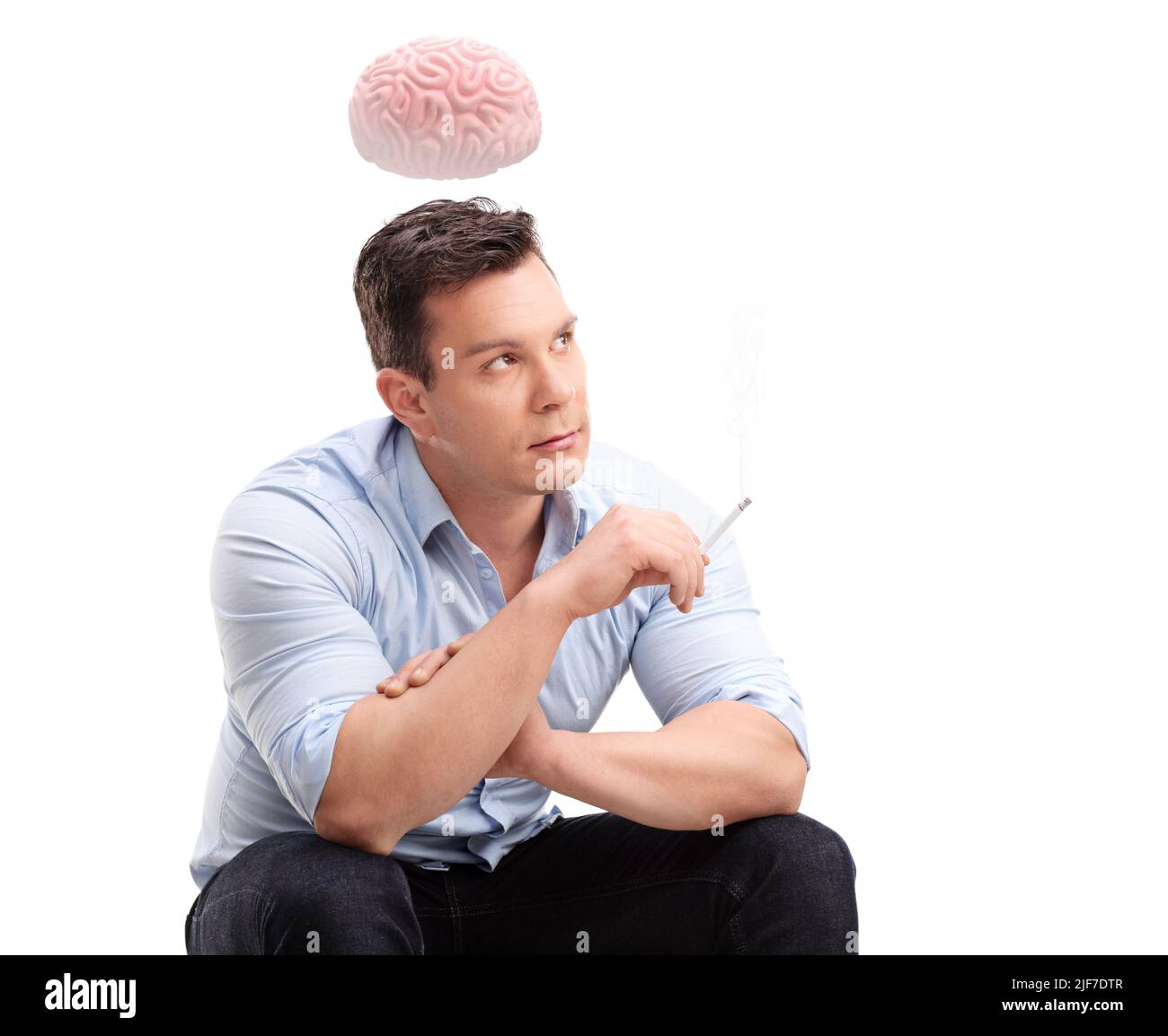 Giovane uomo nervoso che fuma una sigaretta e cervello che galleggia sopra la testa isolato su sfondo bianco Foto Stock