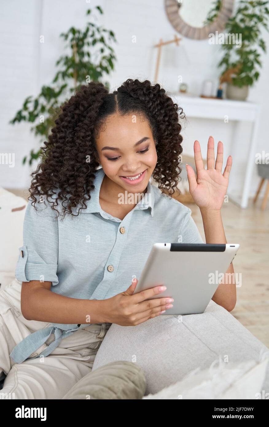 Teen girl afroamericana che agita usando il tablet digitale che ha callt di distanza. Foto Stock
