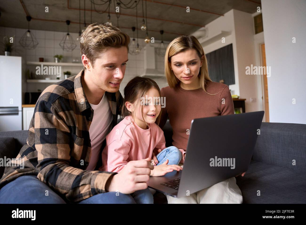 Famiglia felice giovani genitori e figlia bambino utilizzando il computer portatile a casa. Foto Stock