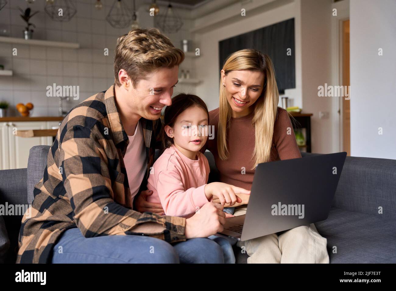 Famiglia felice con il bambino che usa il computer portatile seduto sul divano. Foto Stock