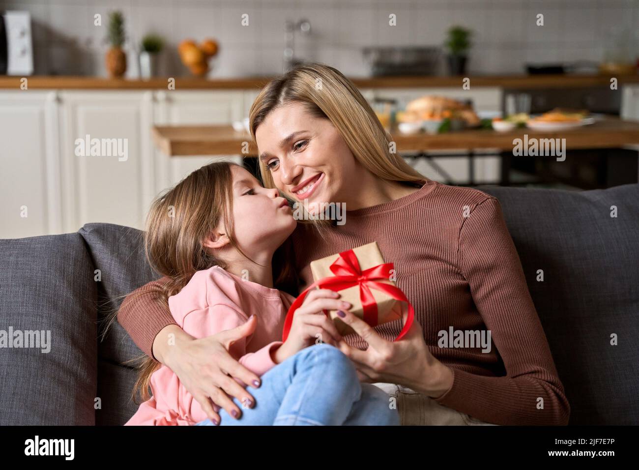 Carino ragazza del bambino di pre che presenta la scatola del regalo che accoglie la mamma felice a casa. Foto Stock