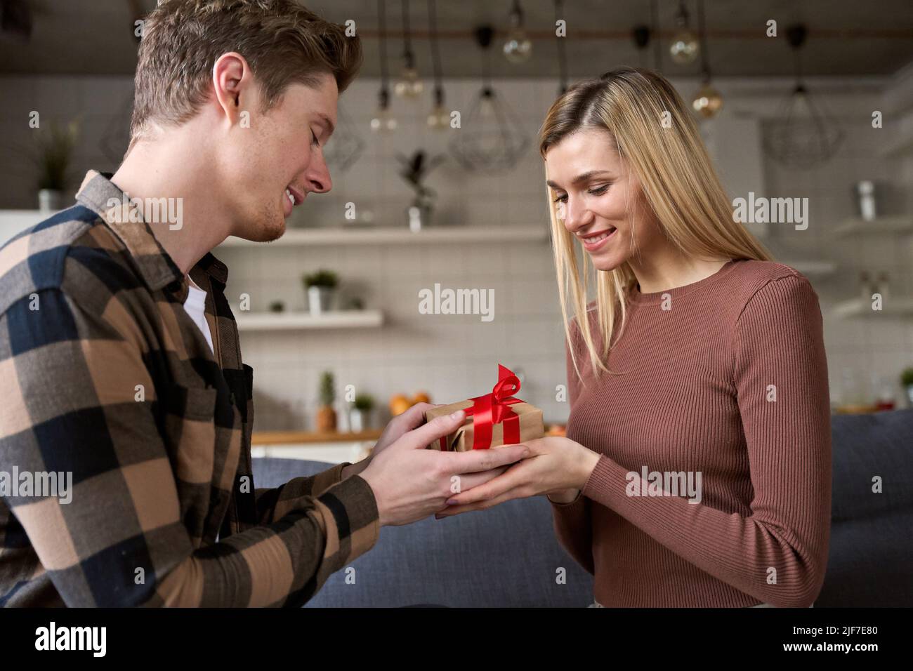 Felice giovane donna che riceve scatola regalo da uomo amorevole a casa Foto Stock