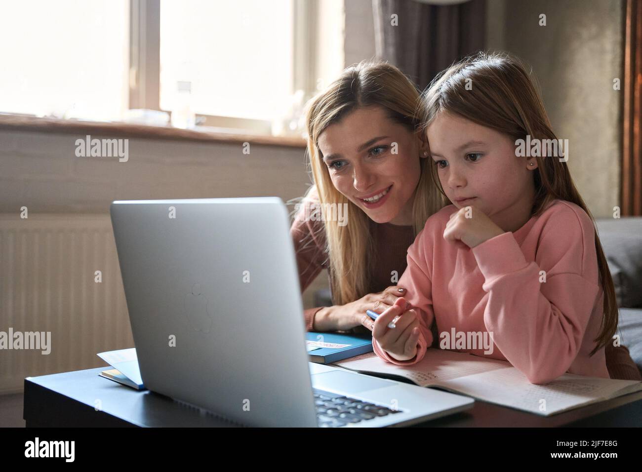 Bambino figlia imparare le classi in linea con la mamma a casa. Foto Stock