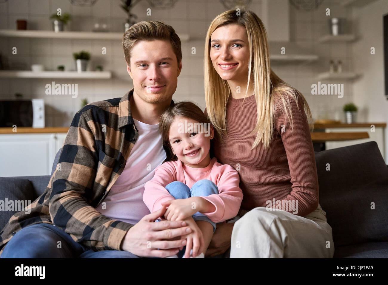 Felice famiglia coppia e bambino figlia che si unisce seduto sul divano a casa. Foto Stock