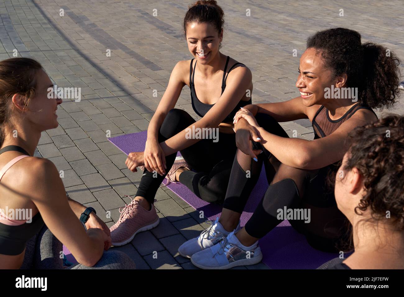 Felice multietnico fit Signore amici parlare ridere dopo gruppo yoga classe all'aperto. Foto Stock