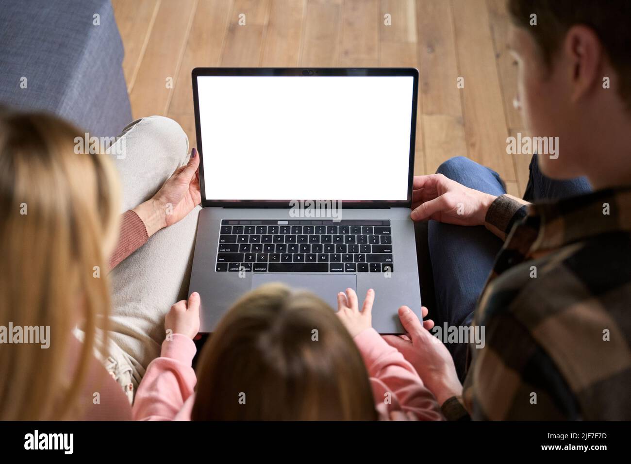 Una famiglia felice che usa lo schermo del computer portatile si siede sul divano di casa. Sopra la spalla Foto Stock