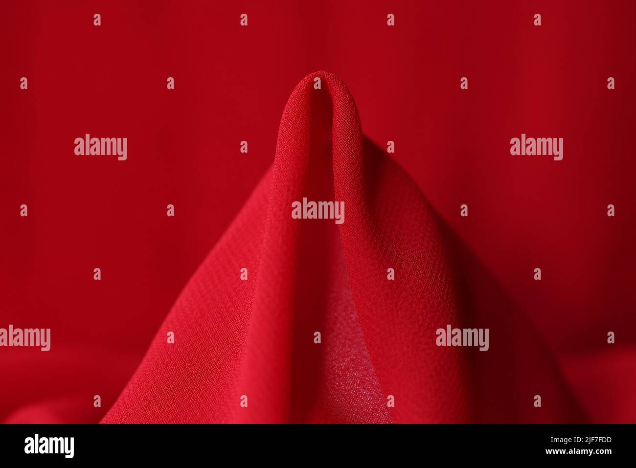 Primo piano in tessuto di seta rossa. Tessuto sintetico di colore rosso brillante Foto Stock