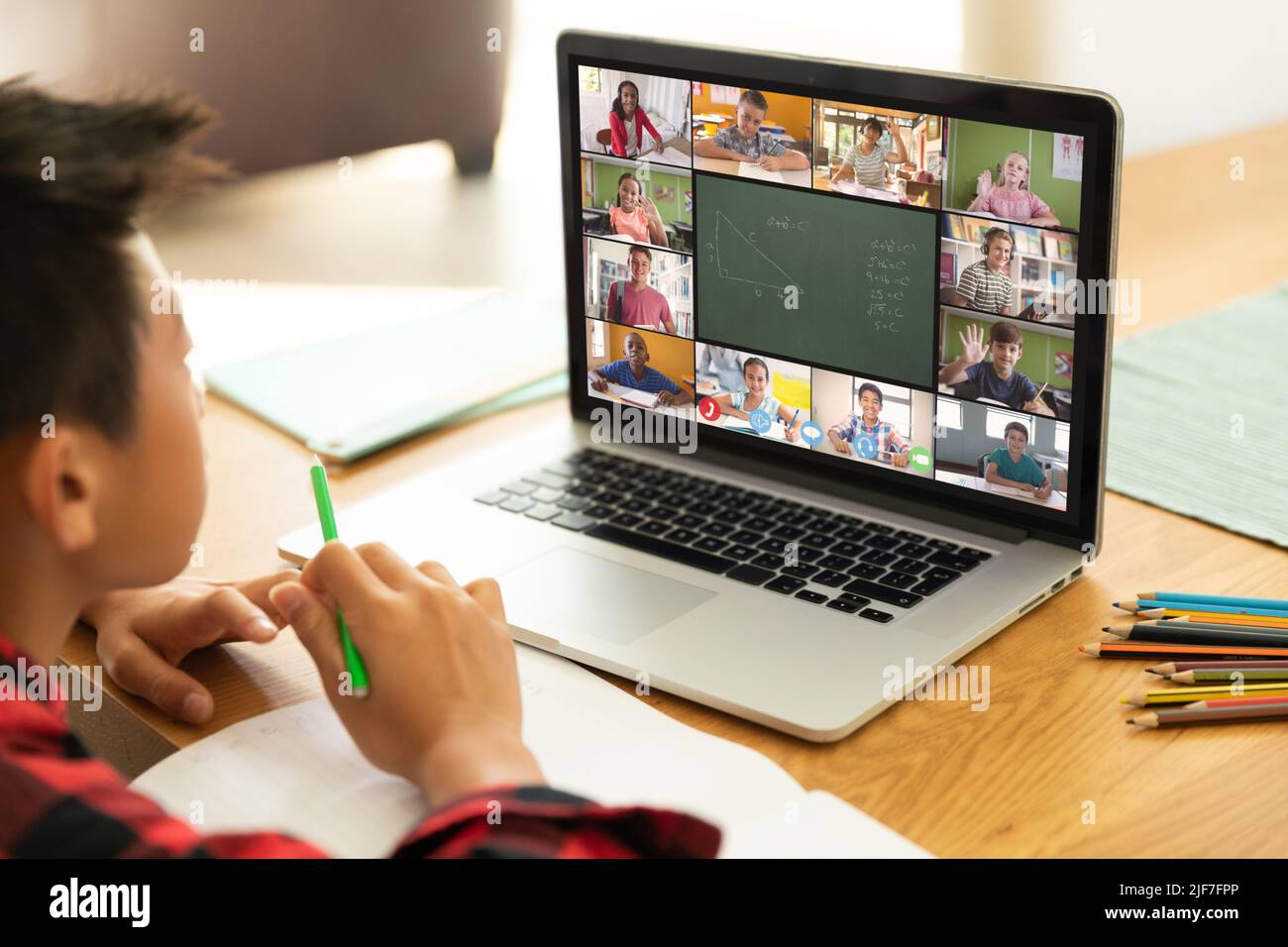 Ragazzo asiatico che guarda attentamente lo schermo del laptop durante le lezioni online a casa Foto Stock