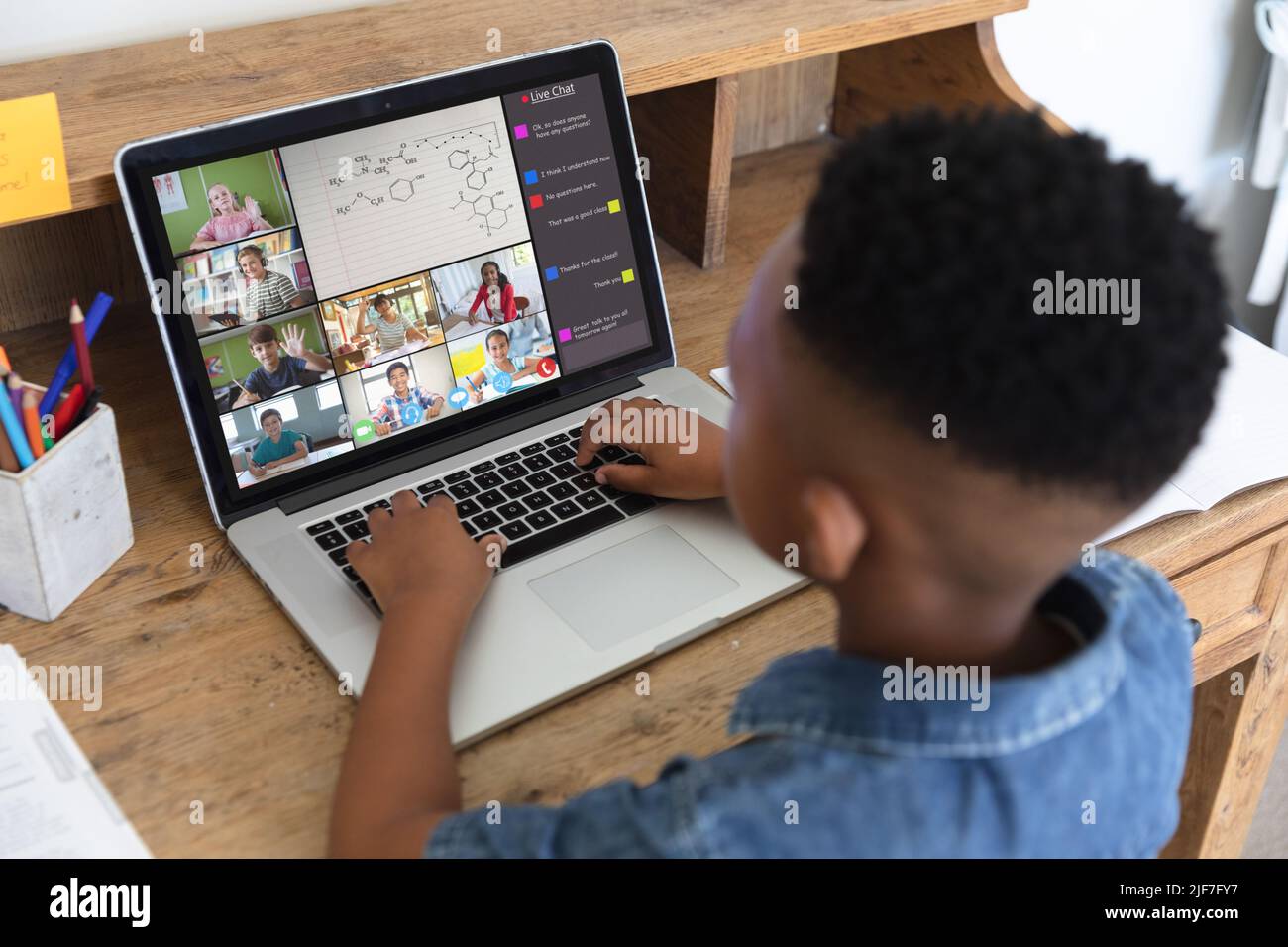 Ragazzo afroamericano che digita messaggio sul laptop durante la videochiamata durante l'apprendimento in classe online Foto Stock