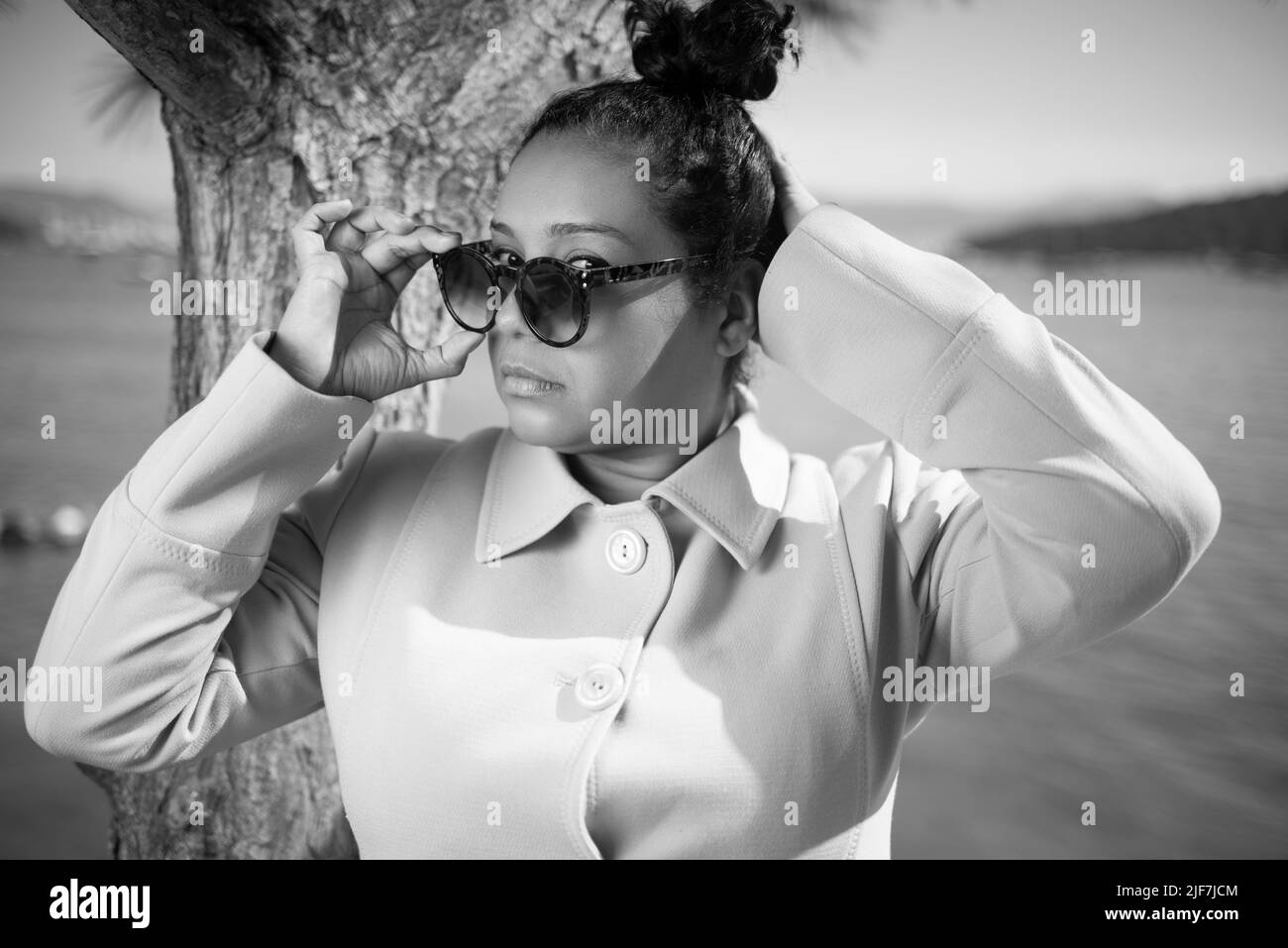 Afro donna che indossa un cappotto e occhiali da sole all'aperto Foto Stock