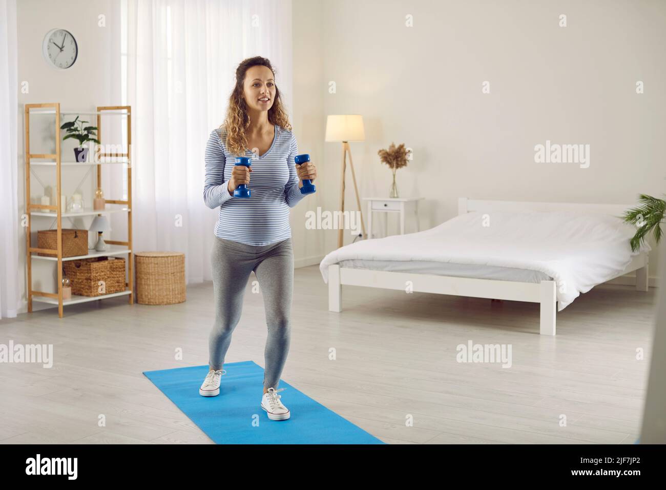 La donna incinta esegue esercizi sportivi a casa per mantenere una buona forma del corpo nel terzo trimestre. Foto Stock