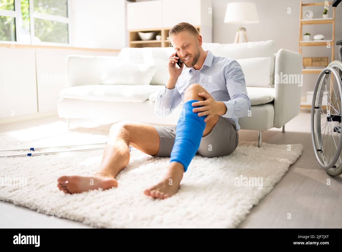 Uomo con lesioni alle gambe utilizzando stampelle a casa Foto Stock