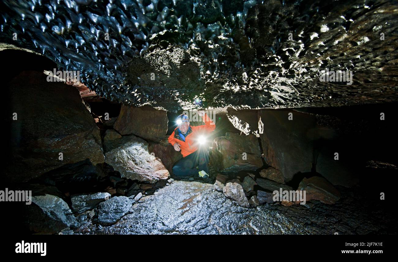 Scienziato che esplora la grotta lavica di Leidarendi in Islanda Foto Stock
