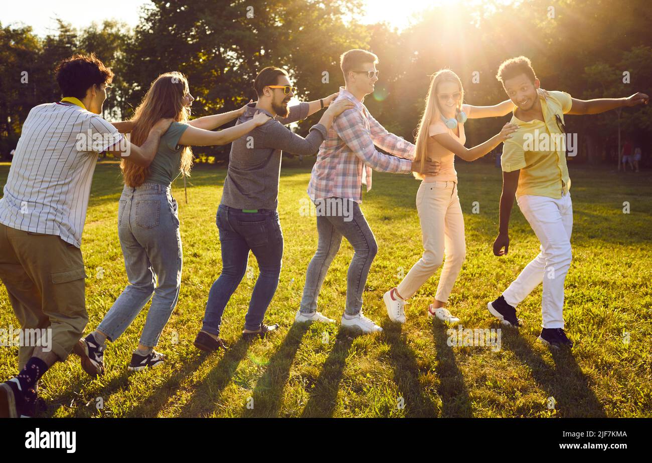 Giovani uomini e donne amichevoli si esibiranno in danza collettiva e divertirsi al party estivo all'aperto Foto Stock