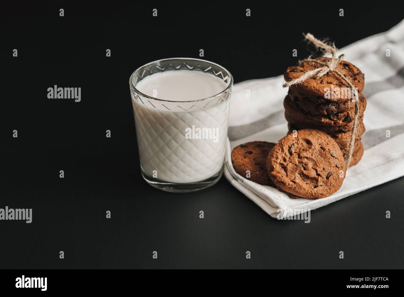 Il bicchiere è riempito con latte e biscotti fatti in casa sul tavolo nero Foto Stock