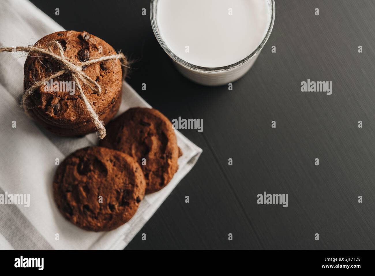 La disposizione piatta di vetro è riempita con latte e biscotti fatti in casa sul tavolo nero Foto Stock