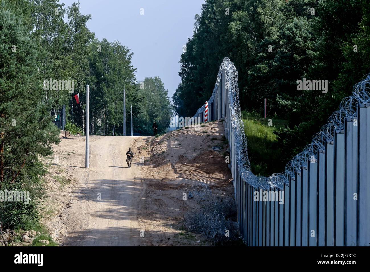 30 giugno 2022, Nowodziel, Polonia: La guardia di frontiera pattuglia le barriere fisiche costruite al confine tra Polonia e Bielorussia. La barriera fu costruita nei primi due trimestri del 2022. Il governo polacco ha deciso di costruire una barriera d'acciaio lunga 186 chilometri e alta 5,5 metri con filo spinato sul confine tra PolishÂ e Bielorussia, che è anche il confine tra l'Unione europea e la NATO. La decisione è stata presa dopo che thousandsÂ di migranti, principalmente provenienti dalla Siria, dall'Iraq e da AfghanistanÂ, tentarono di attraversare la Polonia dalla Bielorussia. Il governo della Bielorussia è stato accusato di orchestrare la migrazione, con l'aiuto di f Foto Stock