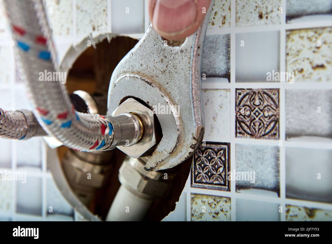 Accessori per impianti idraulici, tubo flessibile intrecciato in acciaio inox tubo per l'acqua per l'alimentazione di acqua calda e fredda a casa esce dal foro nel muro di casa in Foto Stock