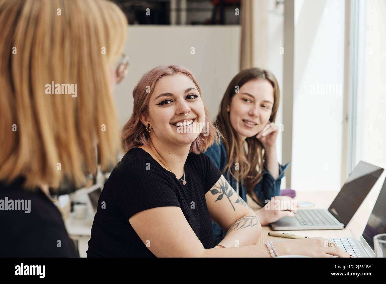 Imprenditori sorridenti che guardano un collega durante la riunione in ufficio Foto Stock