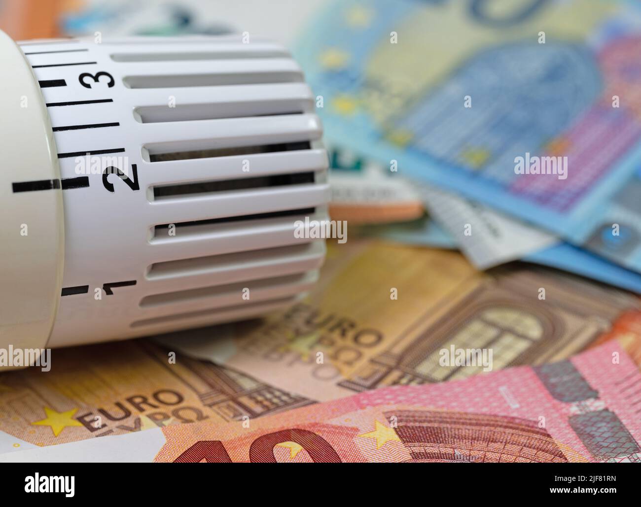 Termostato davanti alle banconote, simbolo dei costi di riscaldamento Foto Stock