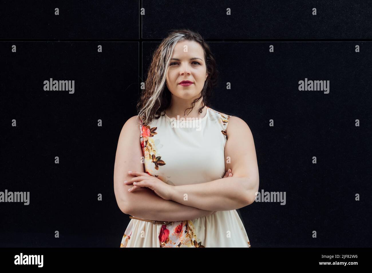 Ritratto di felice fiducioso più taglia curvy giovane donna di fronte al muro nero. Brunette Woman Plus taglia all'aperto Foto Stock