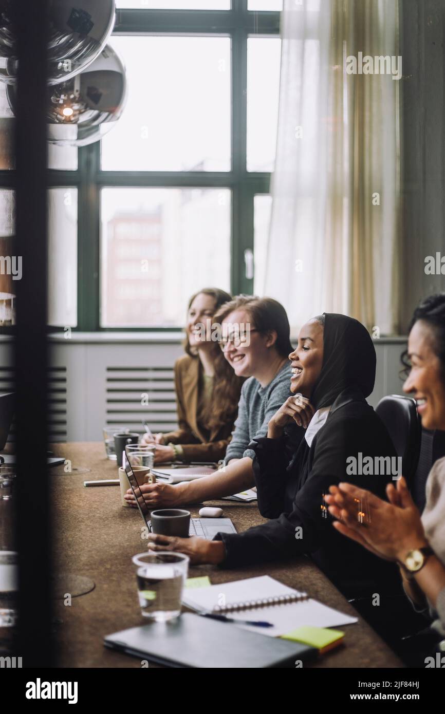 Felice uomo d'affari e donne d'affari che discutono insieme nella sala riunioni Foto Stock