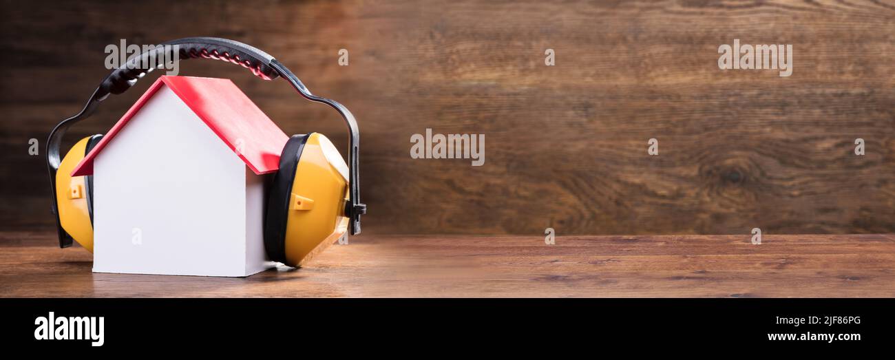Close-up di lavorare giallo cuffia protettiva sul modello della casa sopra il tavolo in legno Foto Stock