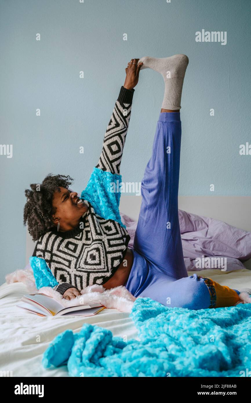 Felice giovane donna che tocca le dita dei piedi mentre si trova in camera da letto Foto Stock