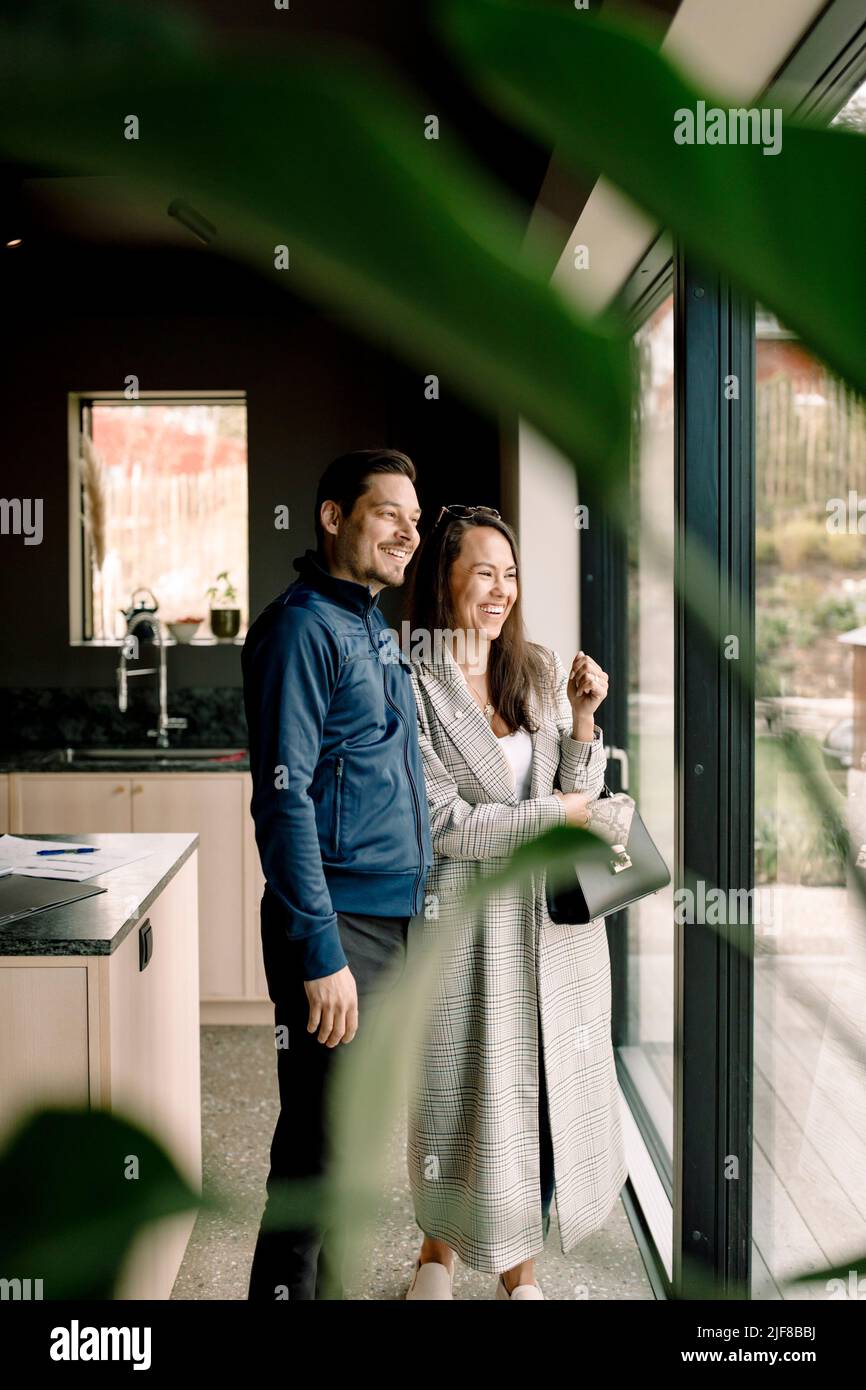 Clienti allegri che guardano attraverso la finestra mentre si trovano in una nuova casa Foto Stock
