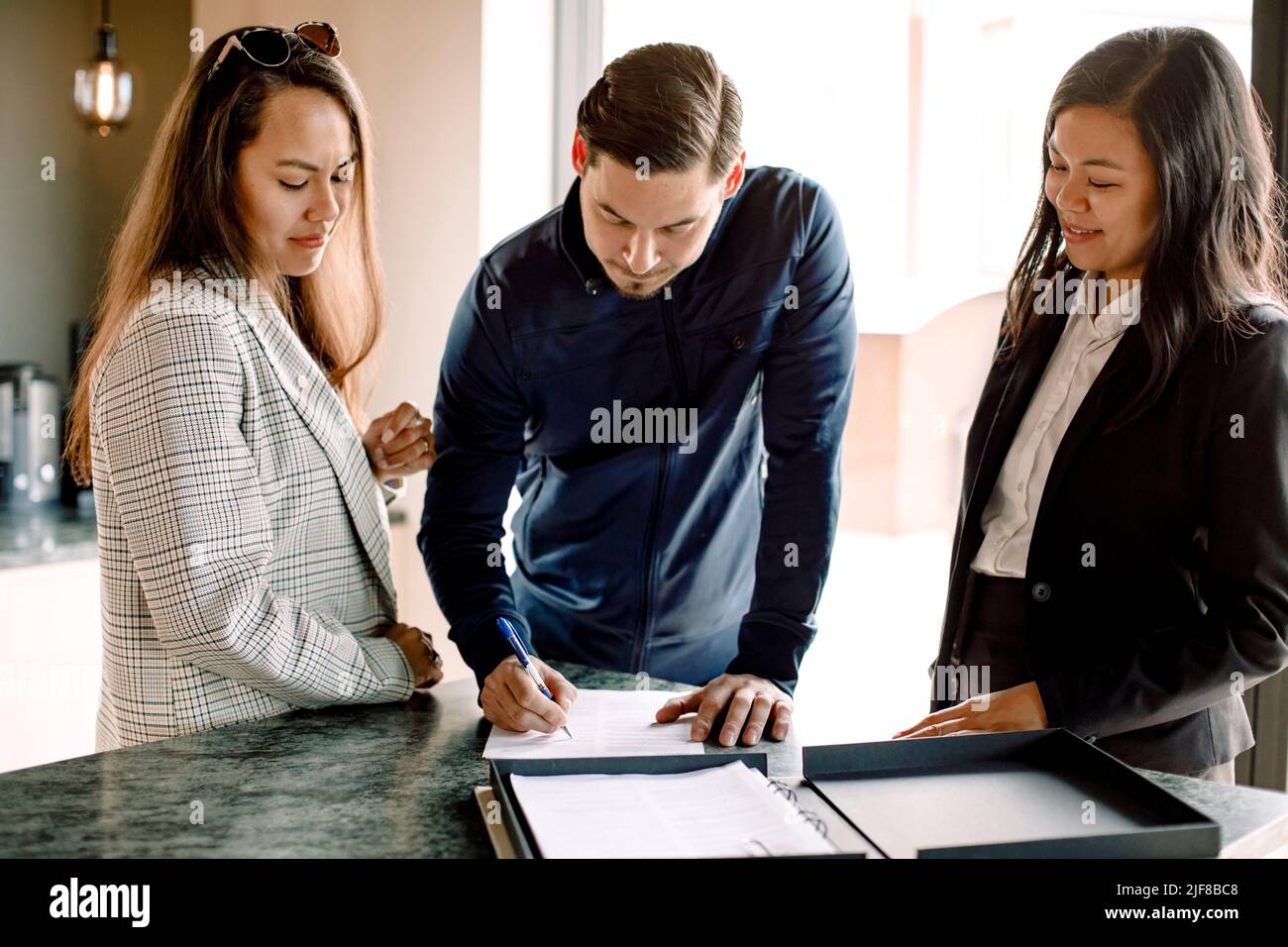 Cliente con agente immobiliare firma contratto in cucina di nuova casa Foto Stock