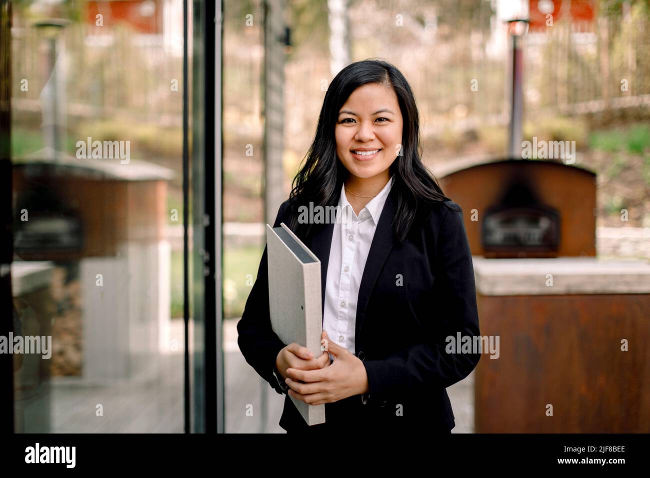 Ritratto di fiducioso agente immobiliare femminile in piedi fuori casa Foto Stock