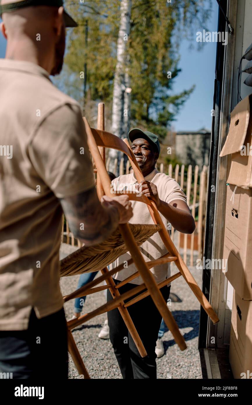 I movers scaricano la sedia dal camion nelle giornate di sole Foto Stock