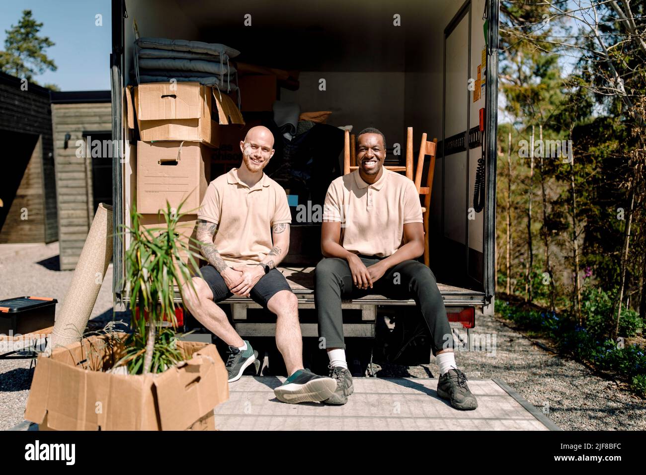 I dipendenti dell'azienda di consegna sorridono mentre si siedono in camion il giorno di sole Foto Stock