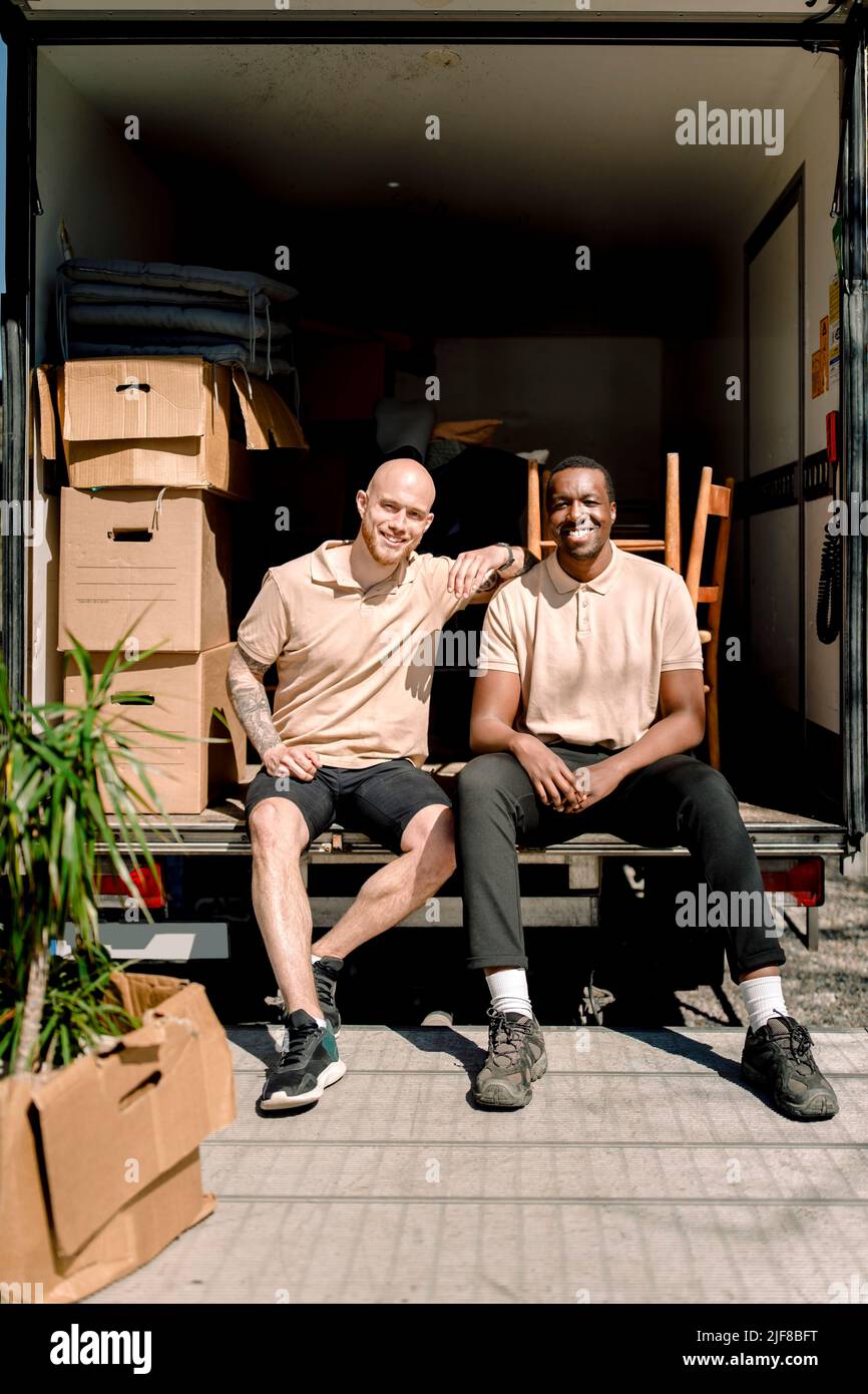 Ritratto di uomini di consegna sorridenti seduti in camion durante la giornata di sole Foto Stock